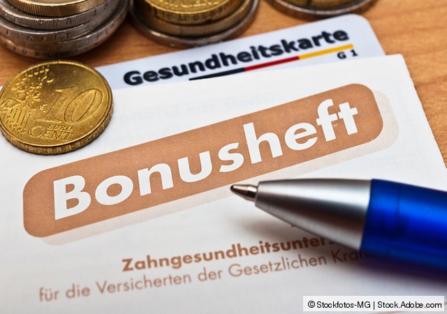 Ein Bonusheft der Krankenkasse, eine Gesundheitskarte und Geldmünzen auf einem Tisch