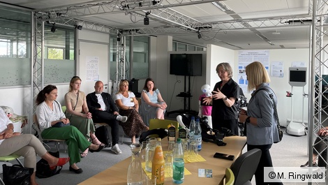 Auf dem Bild sieht man Barbara Klein, die eine Gruppe Menschen begrüßt