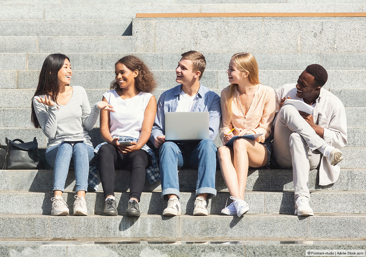 Gruppe diverser Studierende auf der Treppe mit Laptop