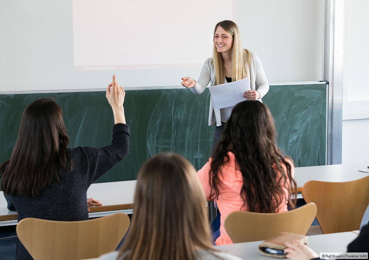Es wird eine Lehrsituation dargestellt, eine Studierende zeigt auf.